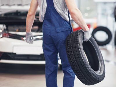 Mechanic holding a tire tire at the repair garage. replacement of winter and summer tires.